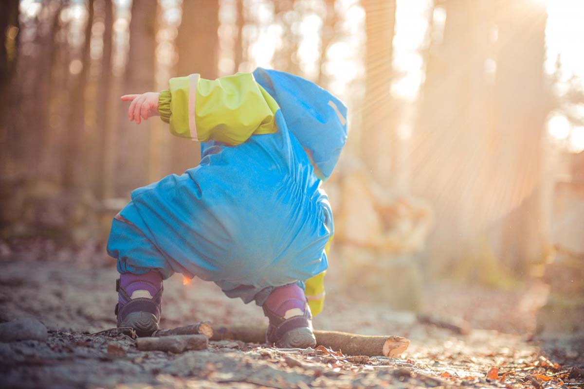 Kleinkind mit Matschsachen spielt im Wald