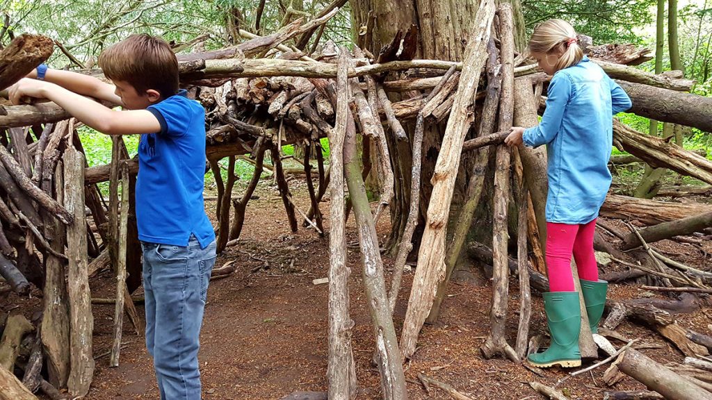 Oudoorkinder bauen mit Ästen im Wald