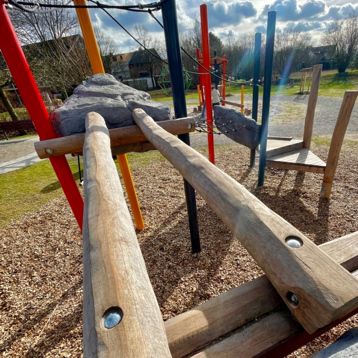 Materialmix aus Stahl, Holz und Stein an einem Klettergerät auf einem Spielplatz der dem Spielplatz Walter-Karentz-Straße in Moers
