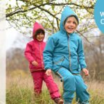 Kinder laufen in Outdoorbekleidung von finkid über eine Wiese
