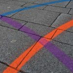 Farbige Linien in orange, lila und blau auf grauem Asphalt