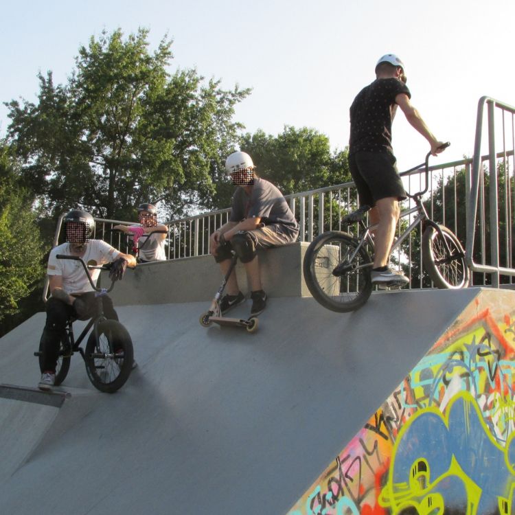 Kinder auf ihren Fahrrädern und Rollern erklimmen eine Rampe auf der Skateanlage des Spielplatzes Bullengraben in Berlin.
